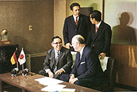 三木プーリの沿革写真 レンゼ社との提携締結風景（机上に日独の国旗を置き伝動機器分野の技術提携に合意する様子）